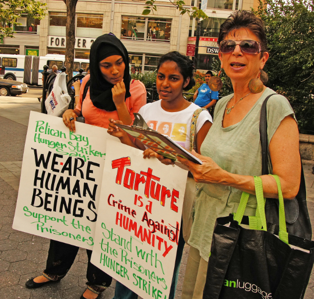 three women hold signs while standing in the street