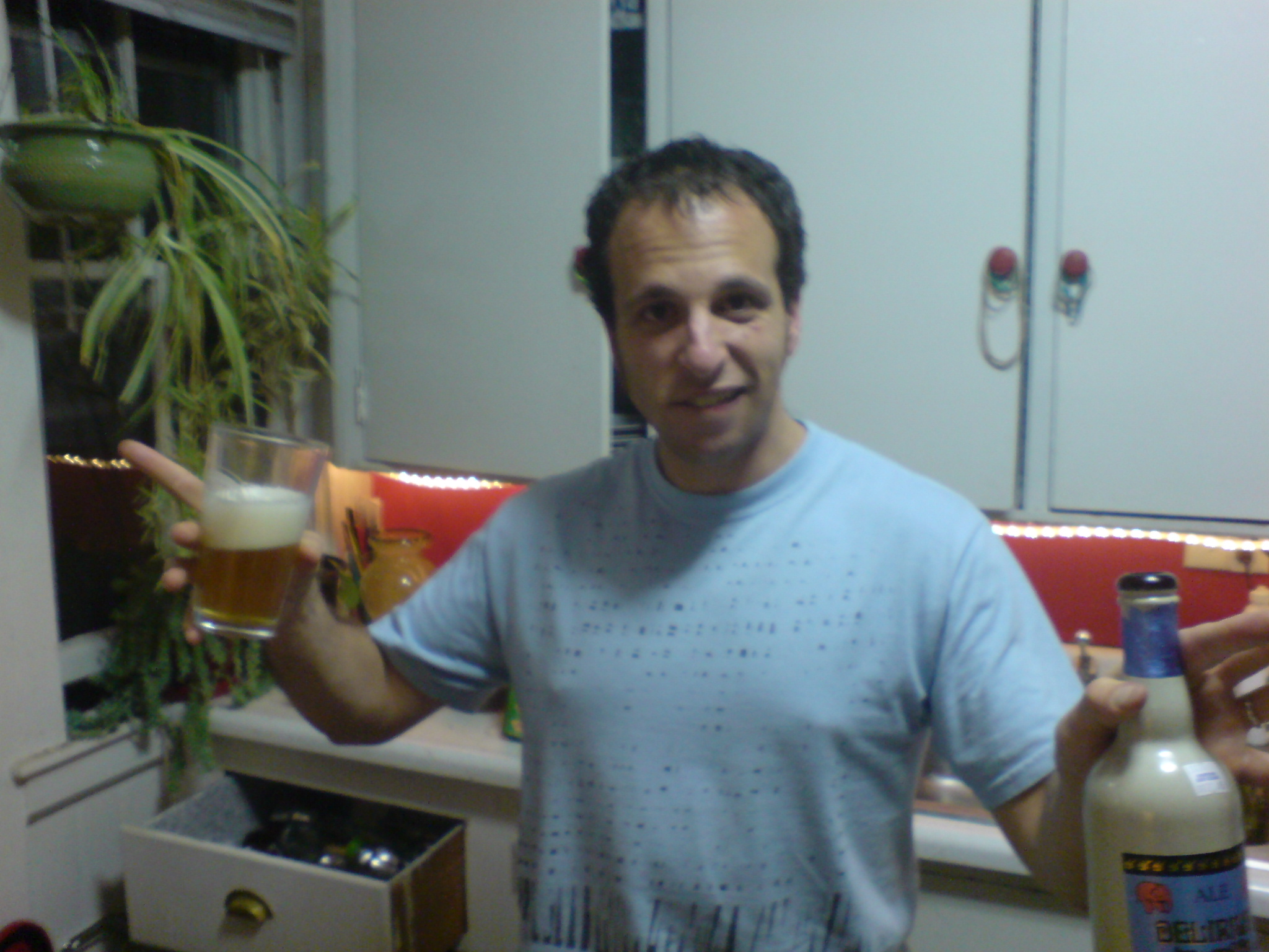 a man holding a beer in a kitchen