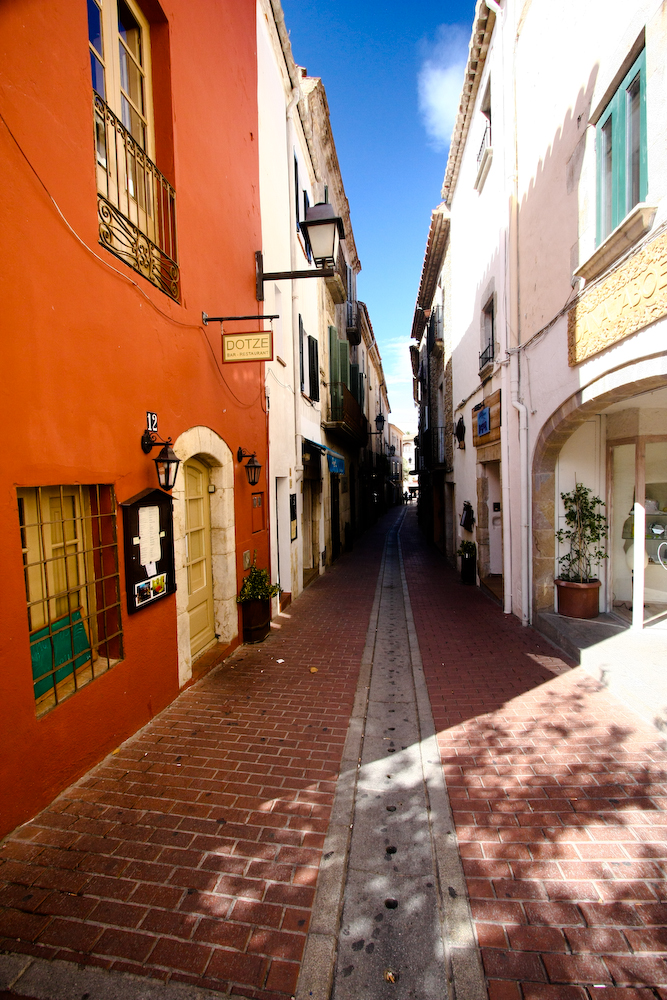 a narrow street lined with tall white buildings