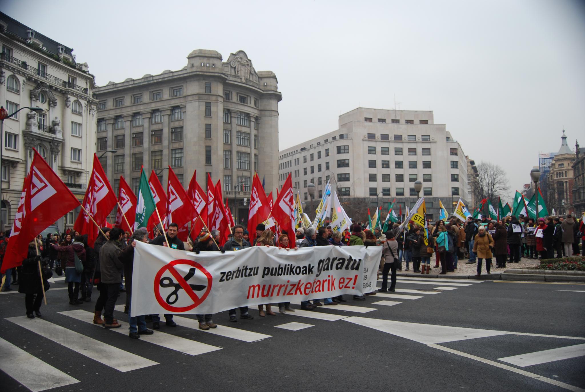 people with flags standing on the street holding red and white flags