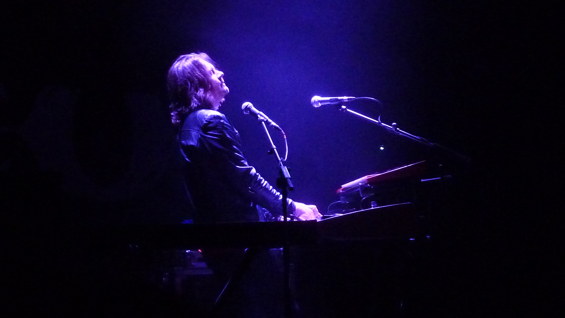 a person standing at a keyboard on stage
