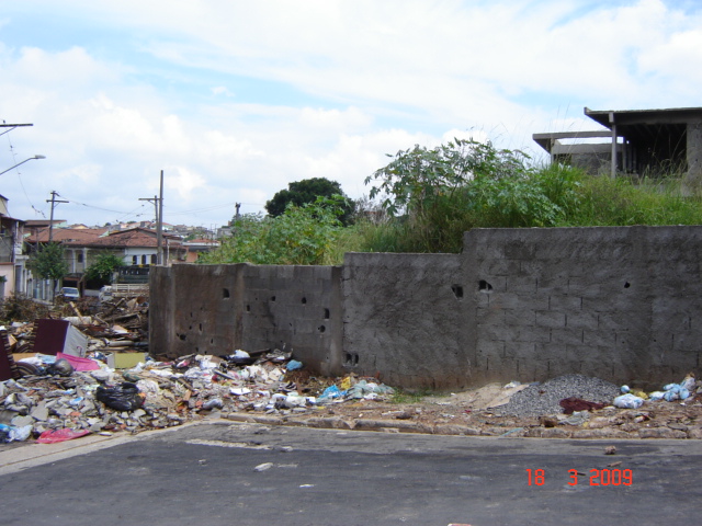 trash piles surrounding a concrete wall and building
