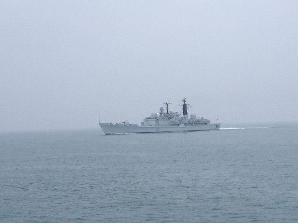 a navy ship sailing across the ocean on a gray day