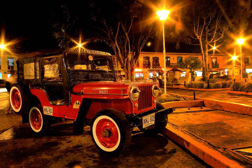 a small jeep parked near lamps in the evening