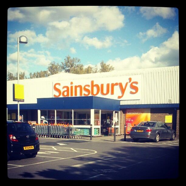 a sainsbury's retail store is shown with a parked car