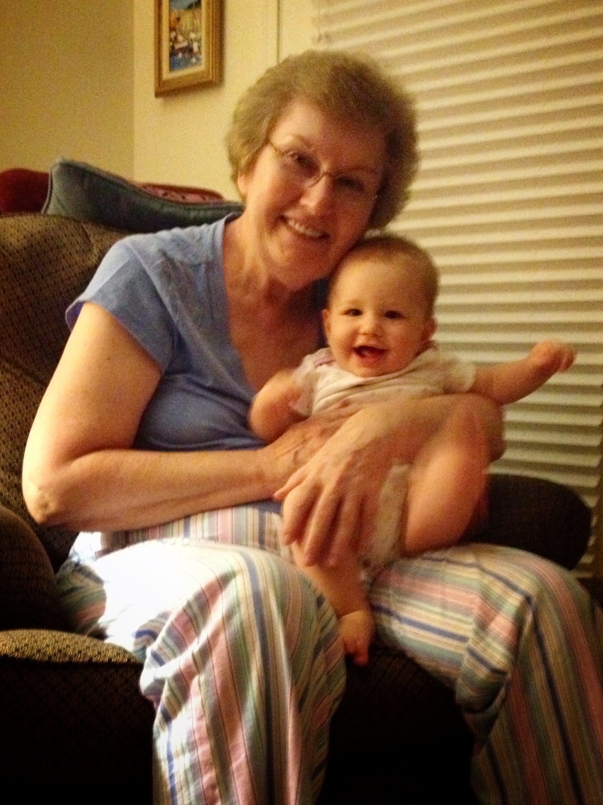 a woman holding a baby who is sitting on a couch