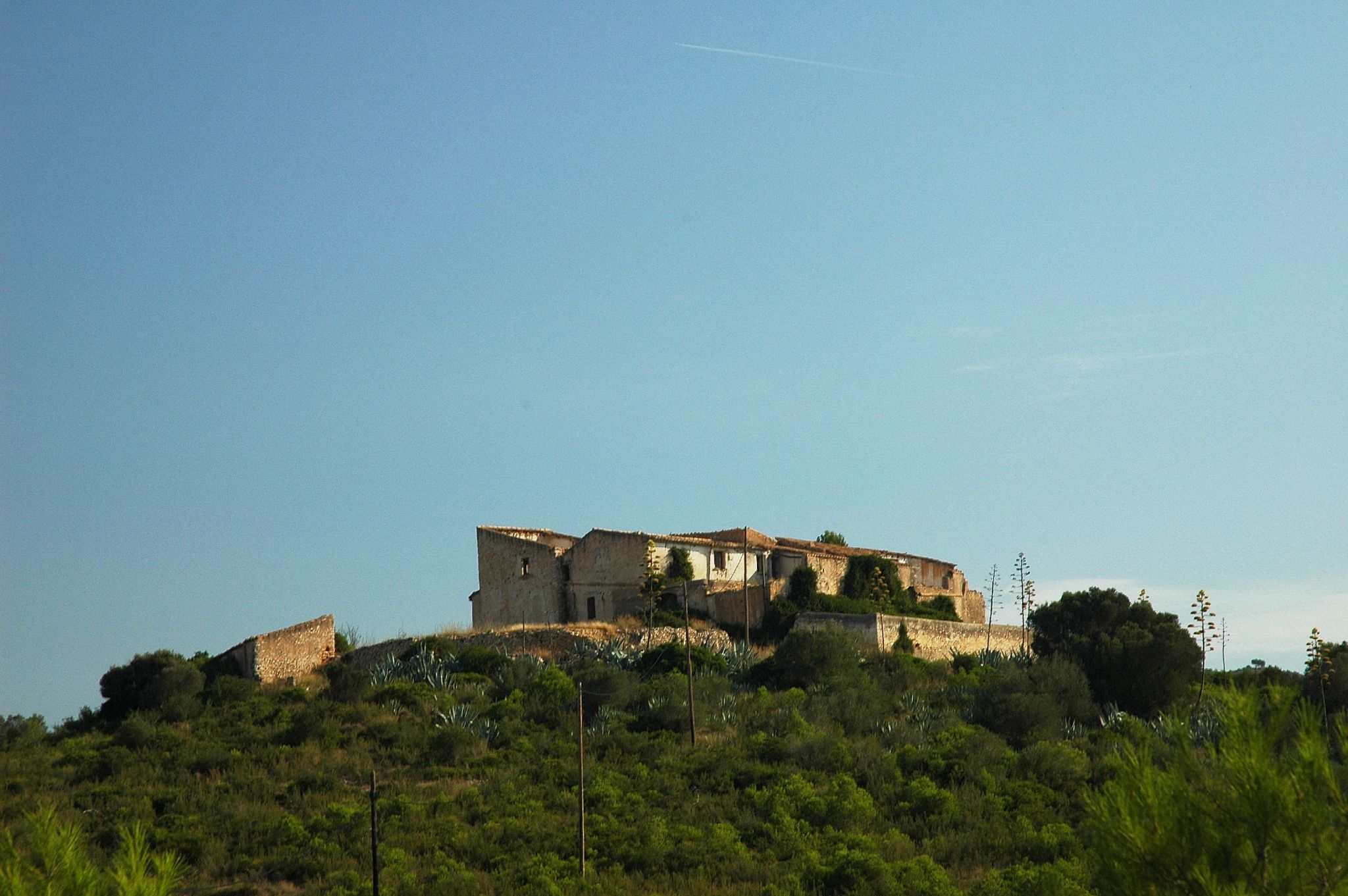 a house on top of a hill, in the distance is cactus