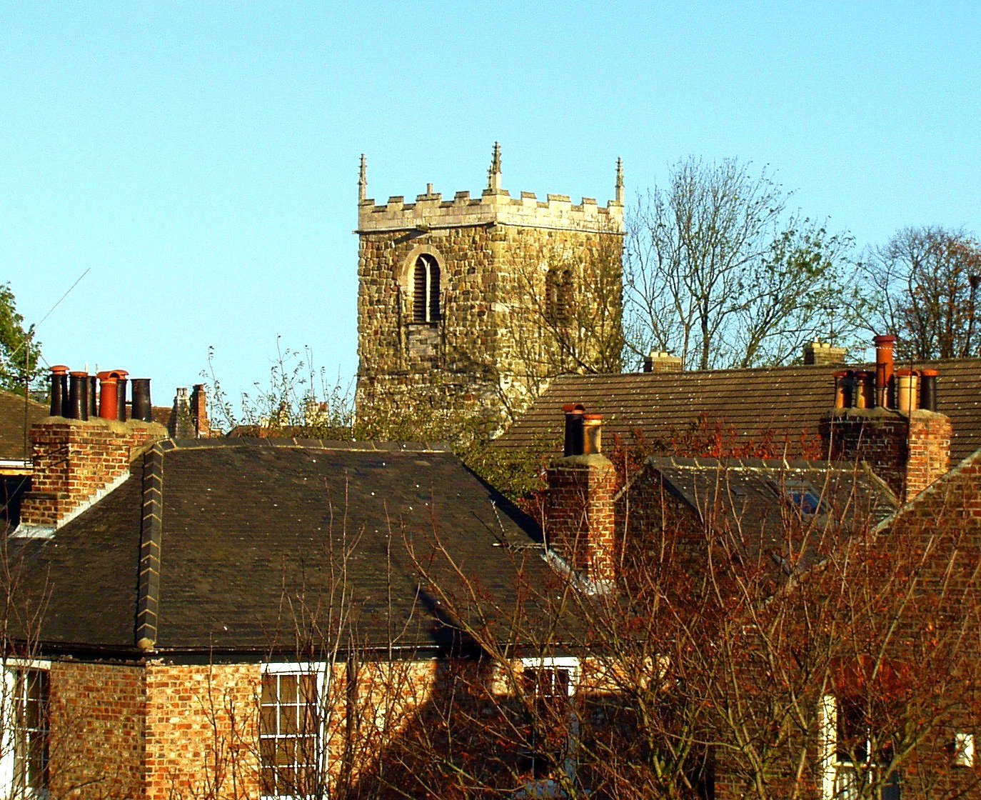 old brick buildings with brick spires sit against a clear blue sky