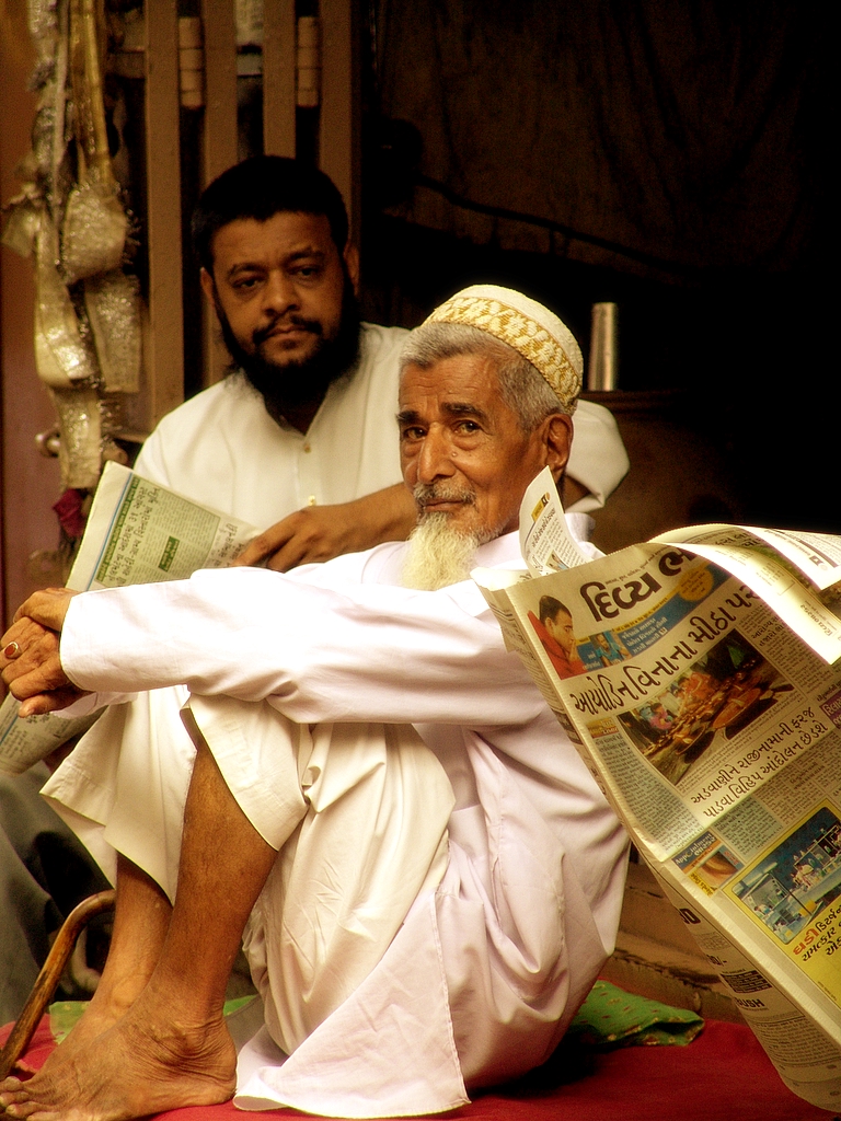 two men sitting on the ground reading newspapers