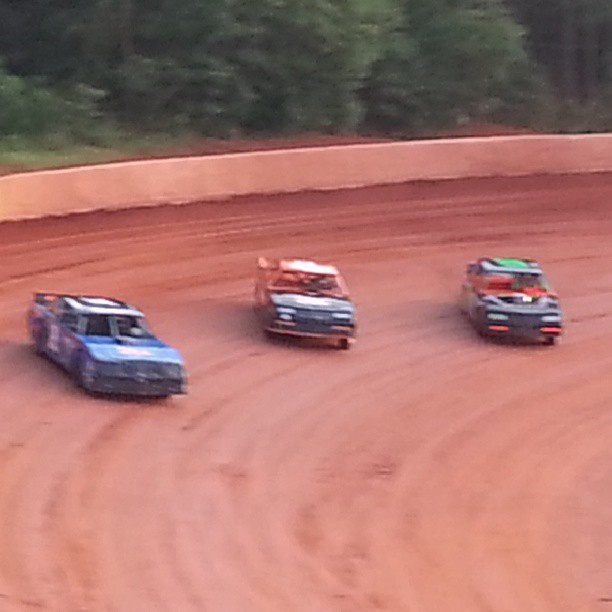 a group of dirt racing cars driving down a track