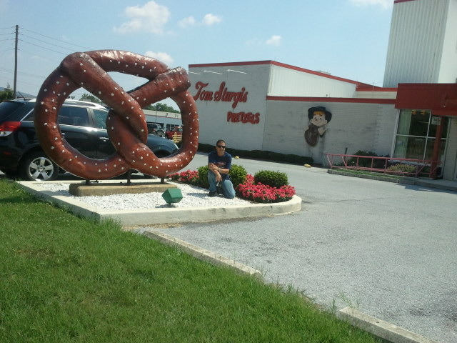 a large brown and white pretzel sculpture next to a car parked in front of the store