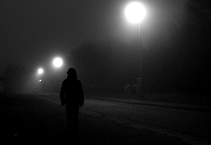 a man walking down the street under lights