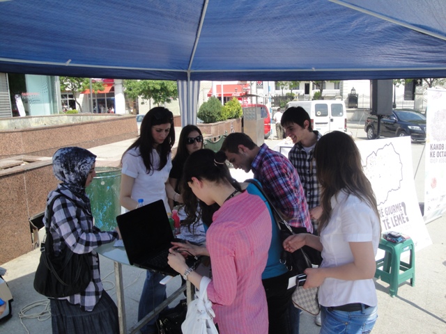 several students gather underneath a tent for a presentation