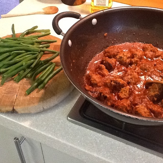 green beans and meat cooked in a pan on the stove