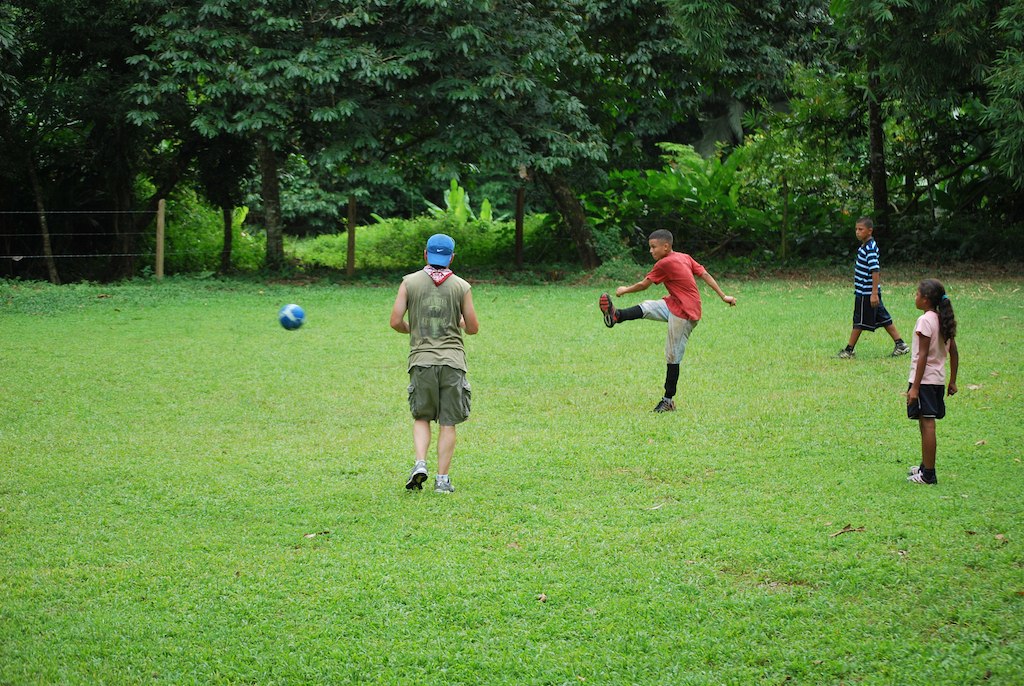 people playing soccer in an open field next to trees