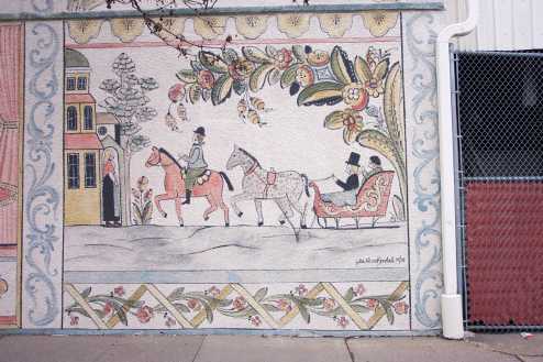 a mosaic on the side of a building, featuring a woman riding a horse and a carriage