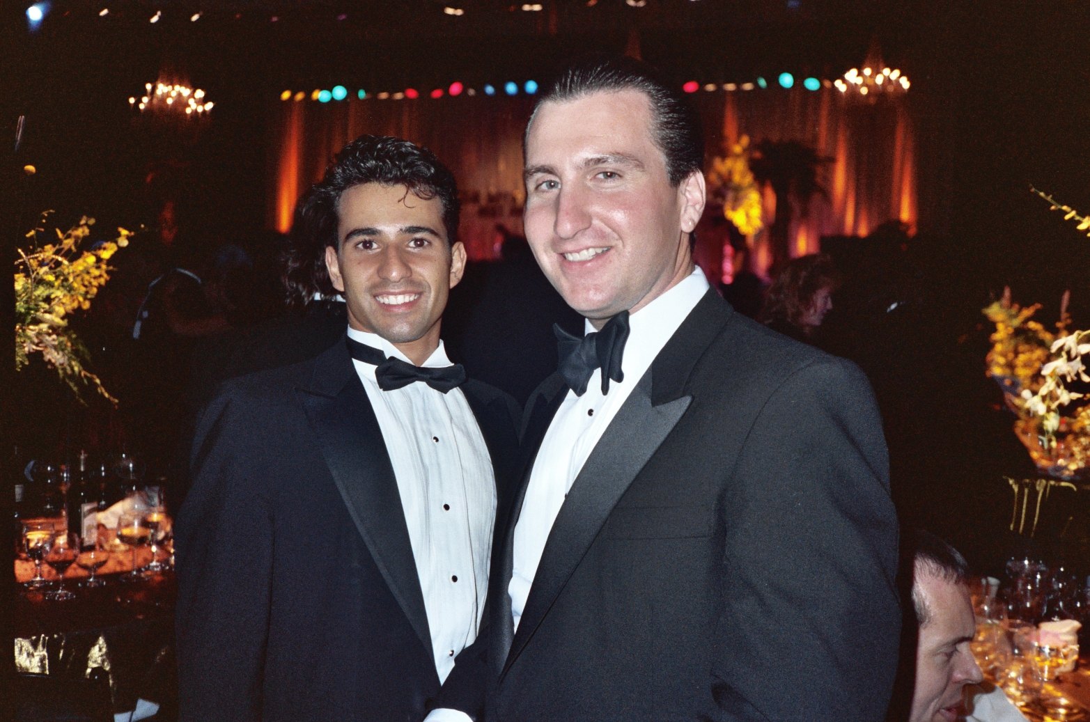 two men dressed in tuxedos posing for a po