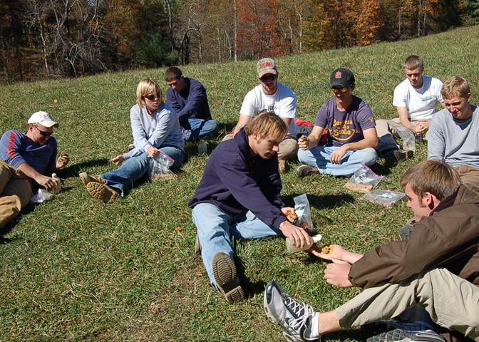 some people sitting around on the ground in a field