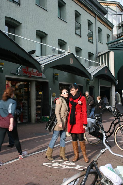 two women are standing near a row of bicycles