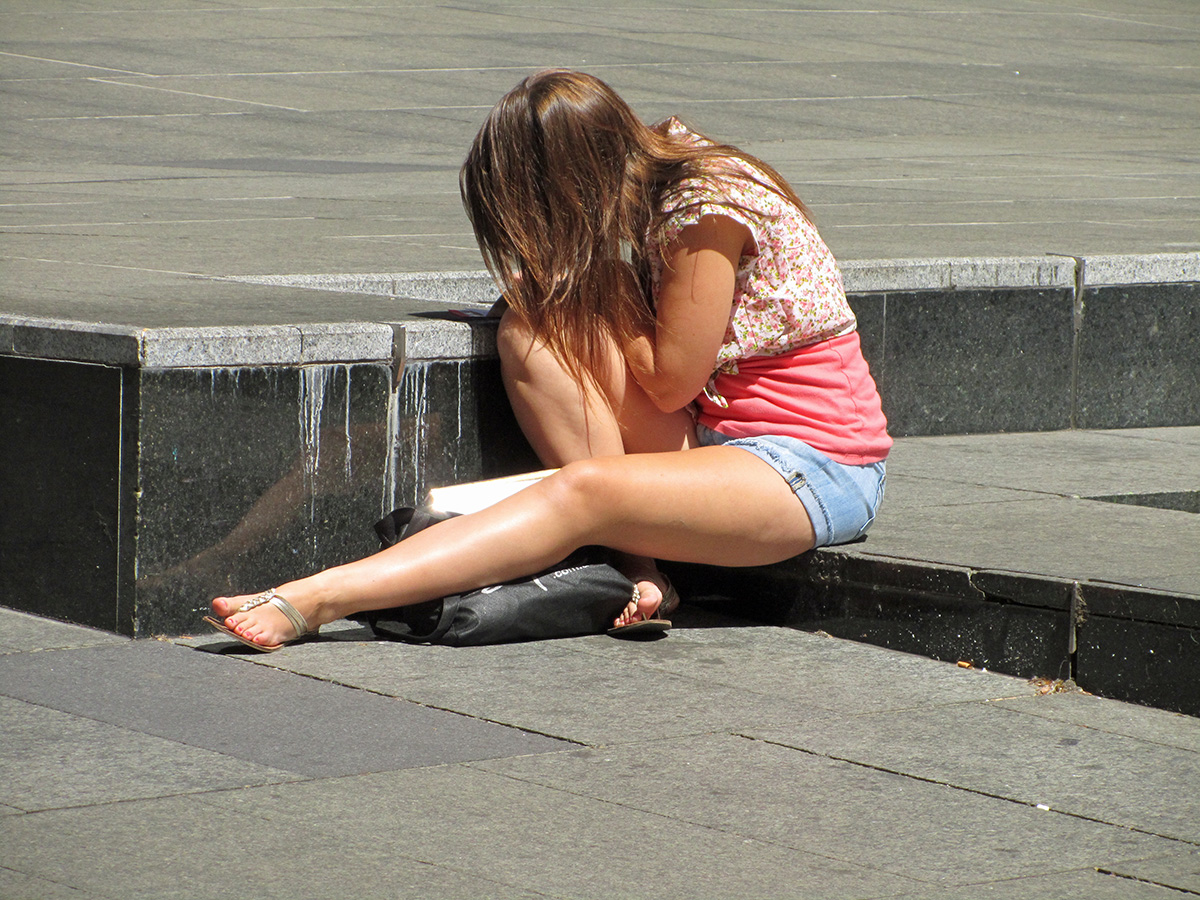 a young woman sitting on the concrete steps and touching her knee