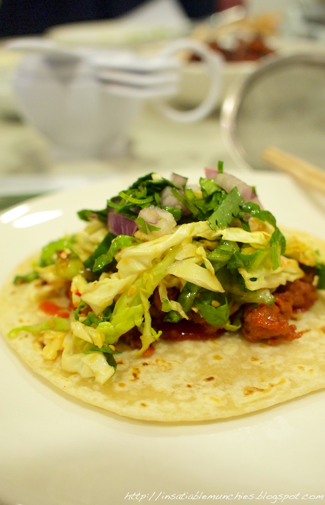 a tortilla on a plate with meat, veggies, and onions