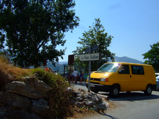 a yellow van drives down a street next to a sign for the park