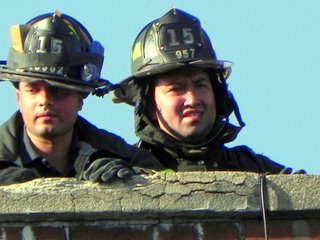 two firefighter are looking over the top of a brick building