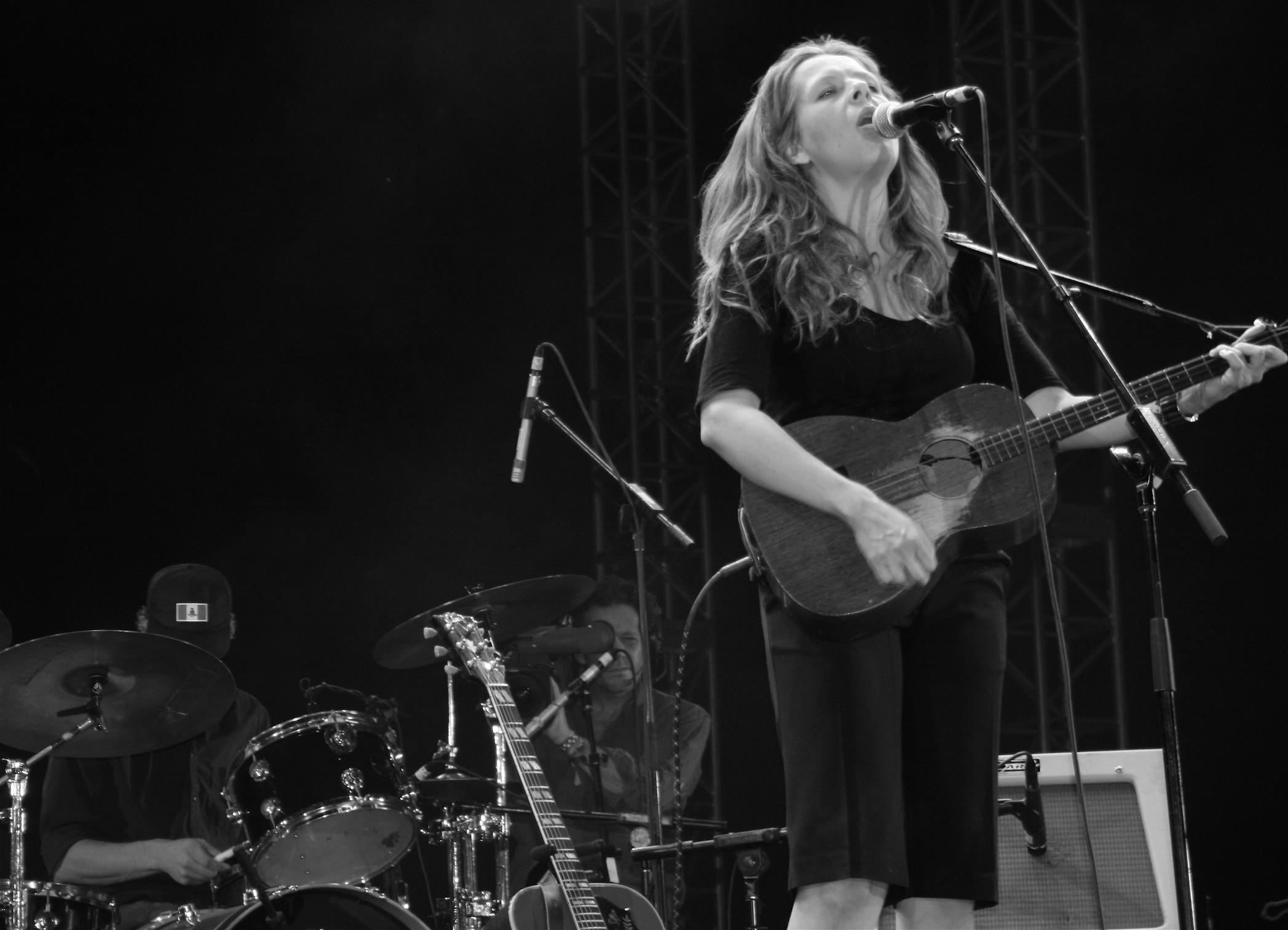 a woman playing guitar in front of a microphone