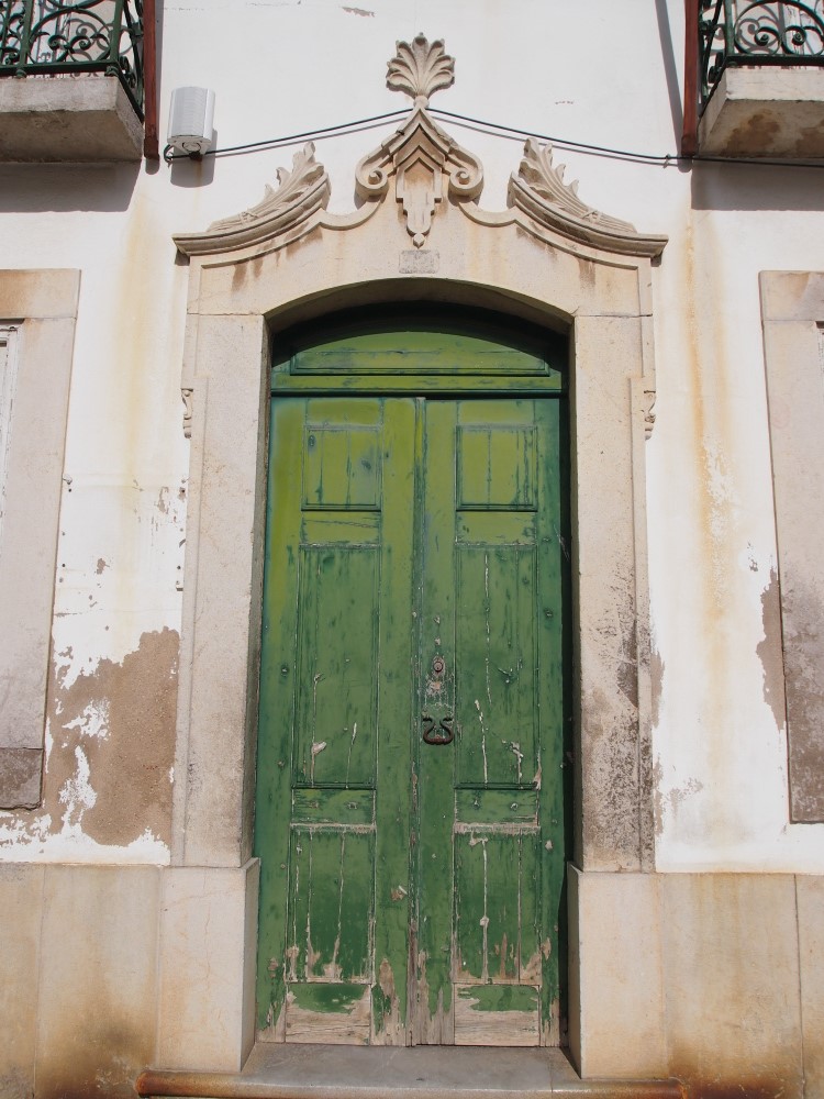 an old building with two green doors on one of it