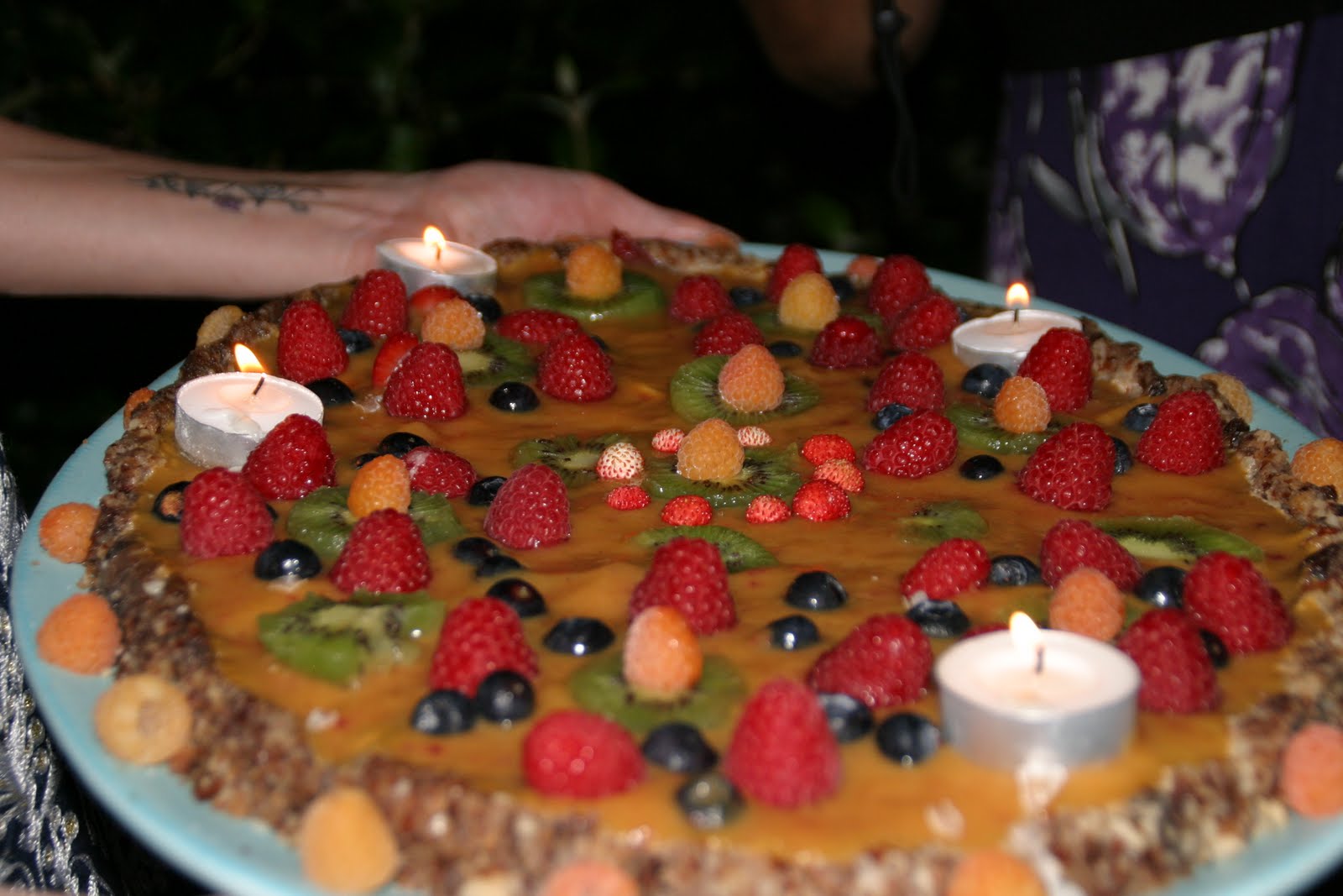 a plate with a cake that has fruit and candles on it