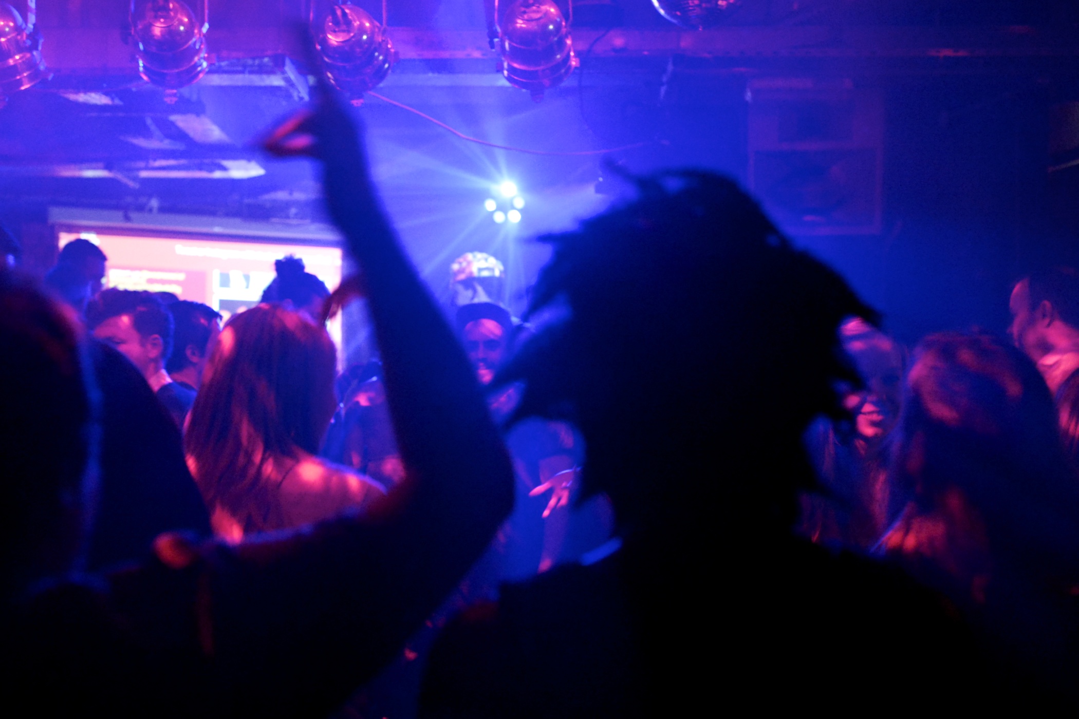 a crowd of people at a nightclub with their arms up