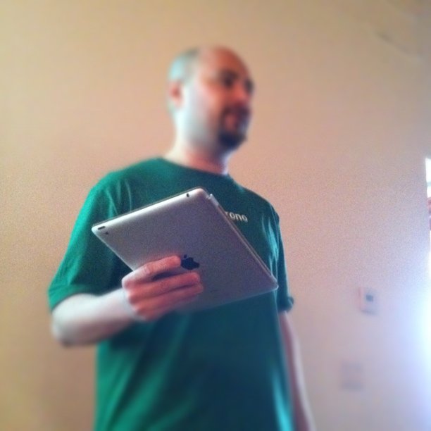 a man wearing green holds an apple tablet