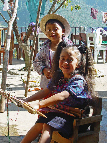 two girls in a small chair with an umbrella