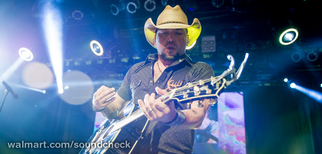 a man wearing a cowboy hat on top of a guitar