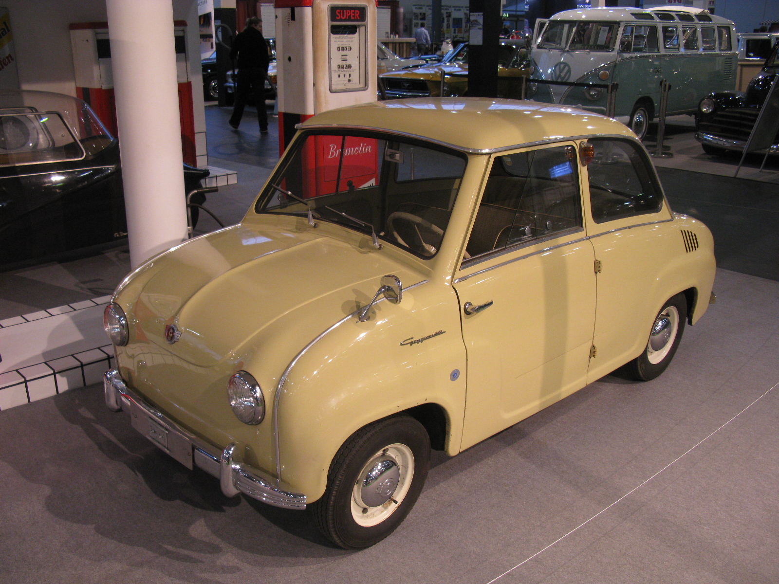 an old yellow car in a museum with other cars