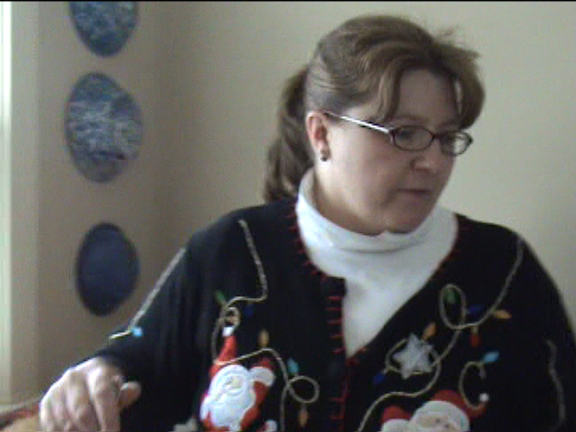 an older woman is holding soing while wearing a sweater