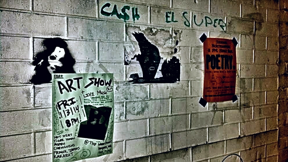 white brick wall decorated with posters, black and green writing