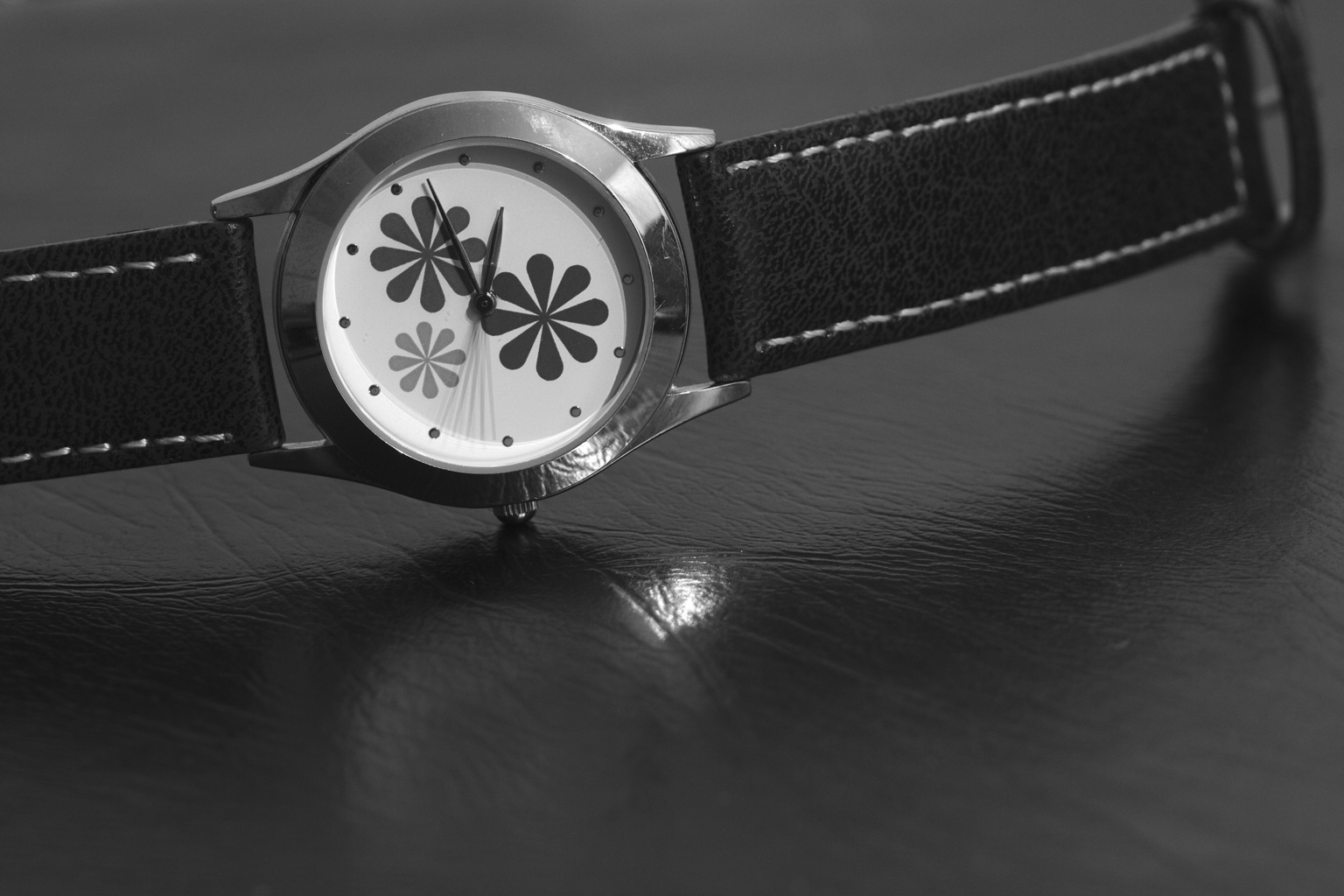 a flower dial on an elegant black strap watch