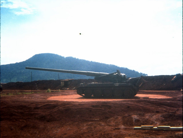 a tank is seen in the distance, and there are hills behind it