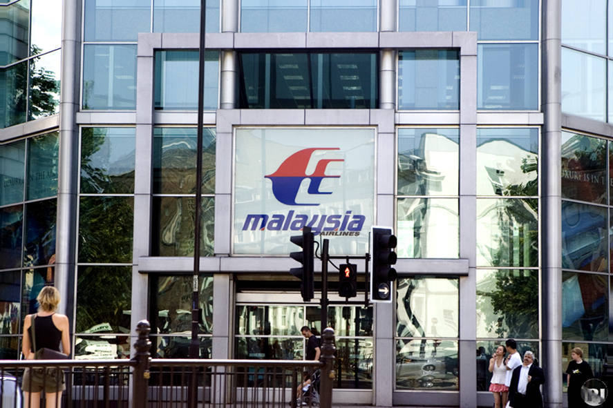 a view of a building from the sidewalk with the malaysia logo on the side