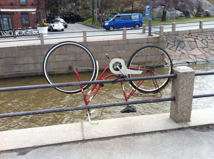an old bicycle on display near water on a city street