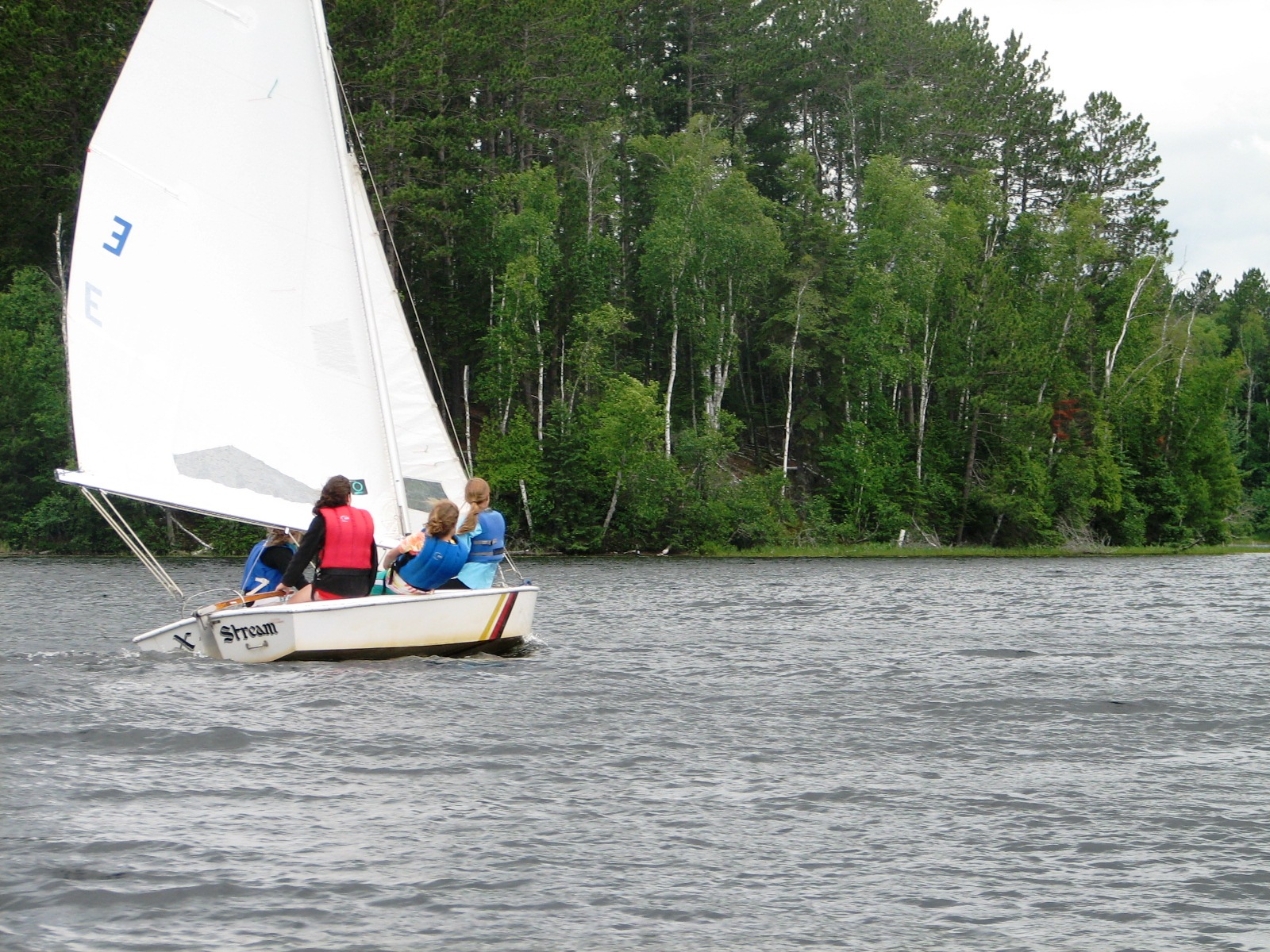 the three people on the sailboat are enjoying the day