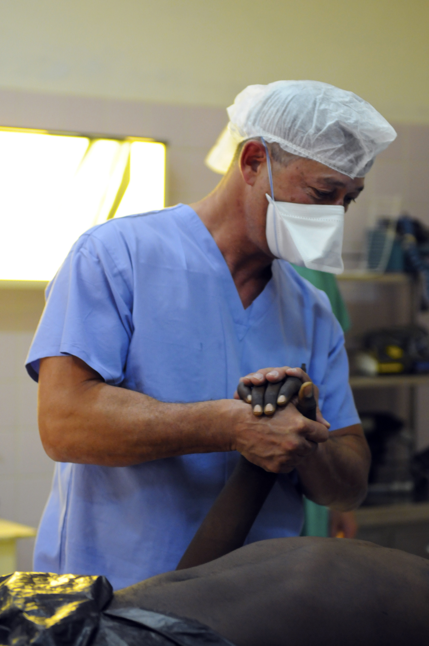 a man in blue scrubs his hands with a medical mask