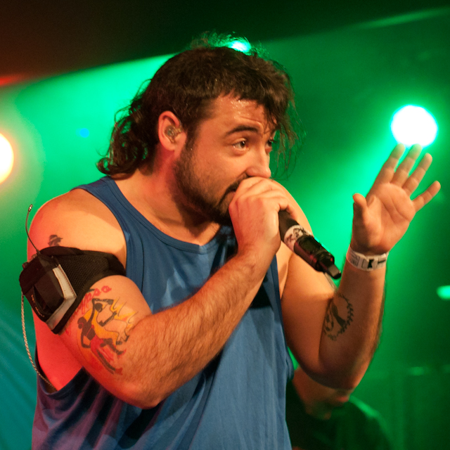 a man with a bandage on his arm holding a microphone in front of green lights