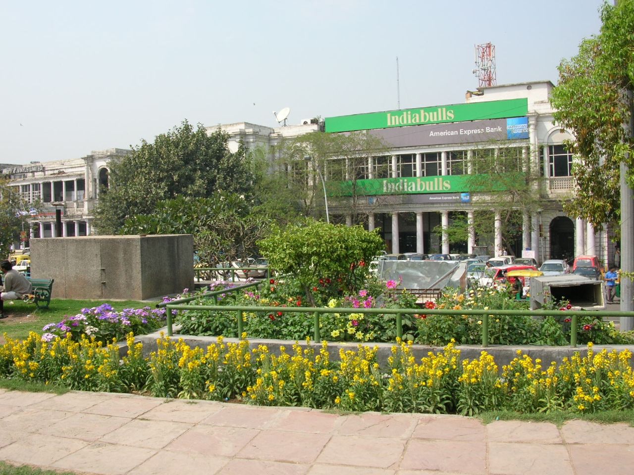 a green building next to yellow flowers and trees