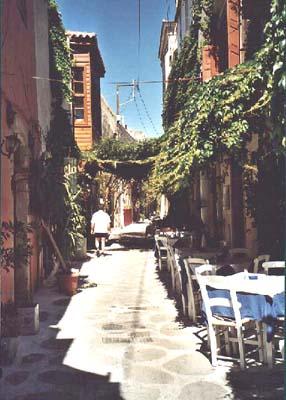 long narrow alley street lined with buildings, with tables and chairs