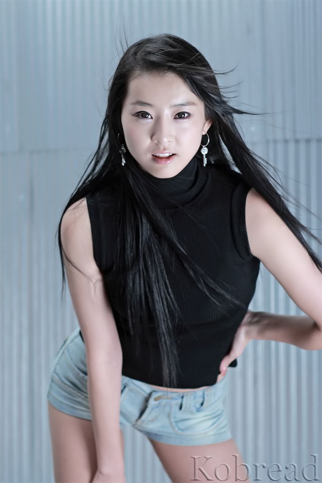 a young woman posing in front of a wall