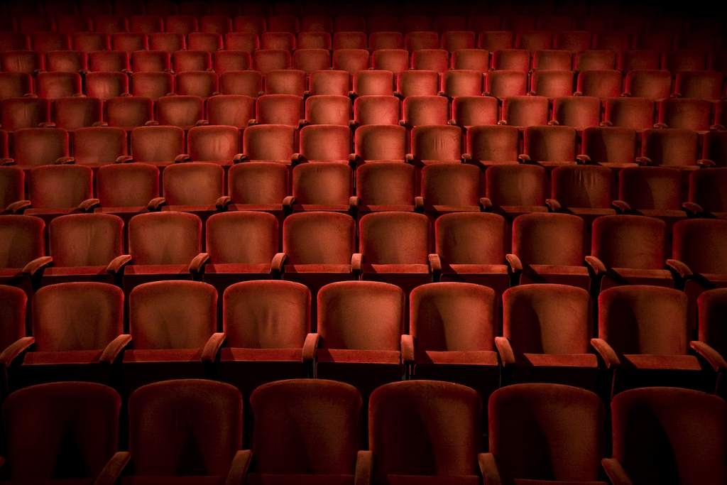 an auditorium with rows of red velvet chairs