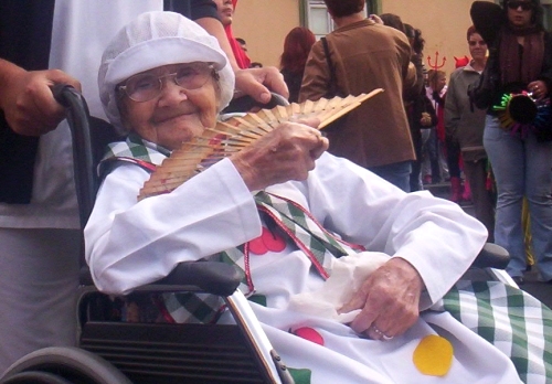 an elderly person sitting on a chair holding a candy cane