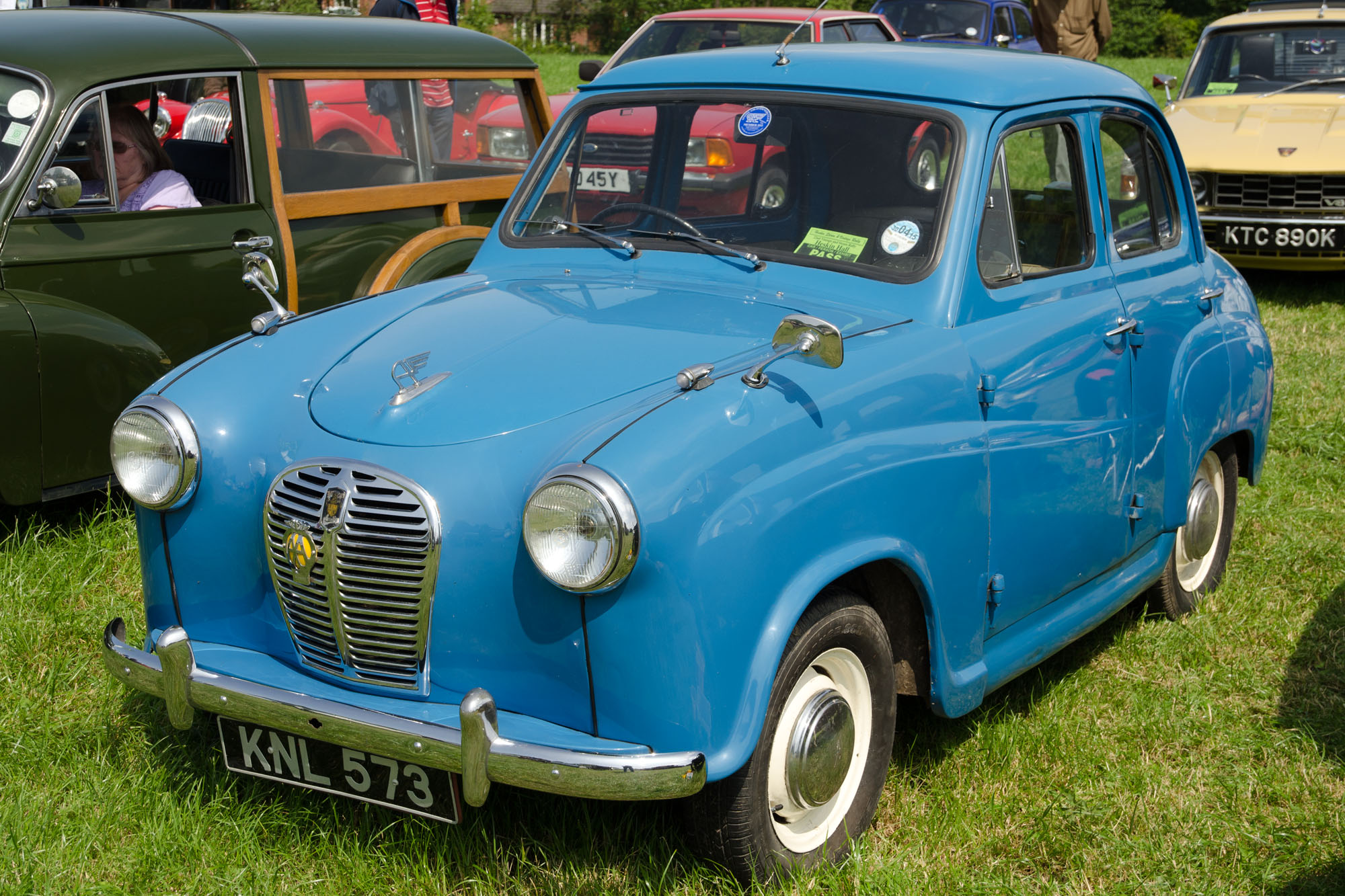 a line up of old cars parked together in the grass